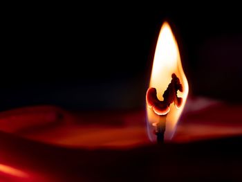 Close-up of lit candle in the dark