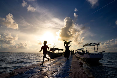 People on beach against sky during sunset