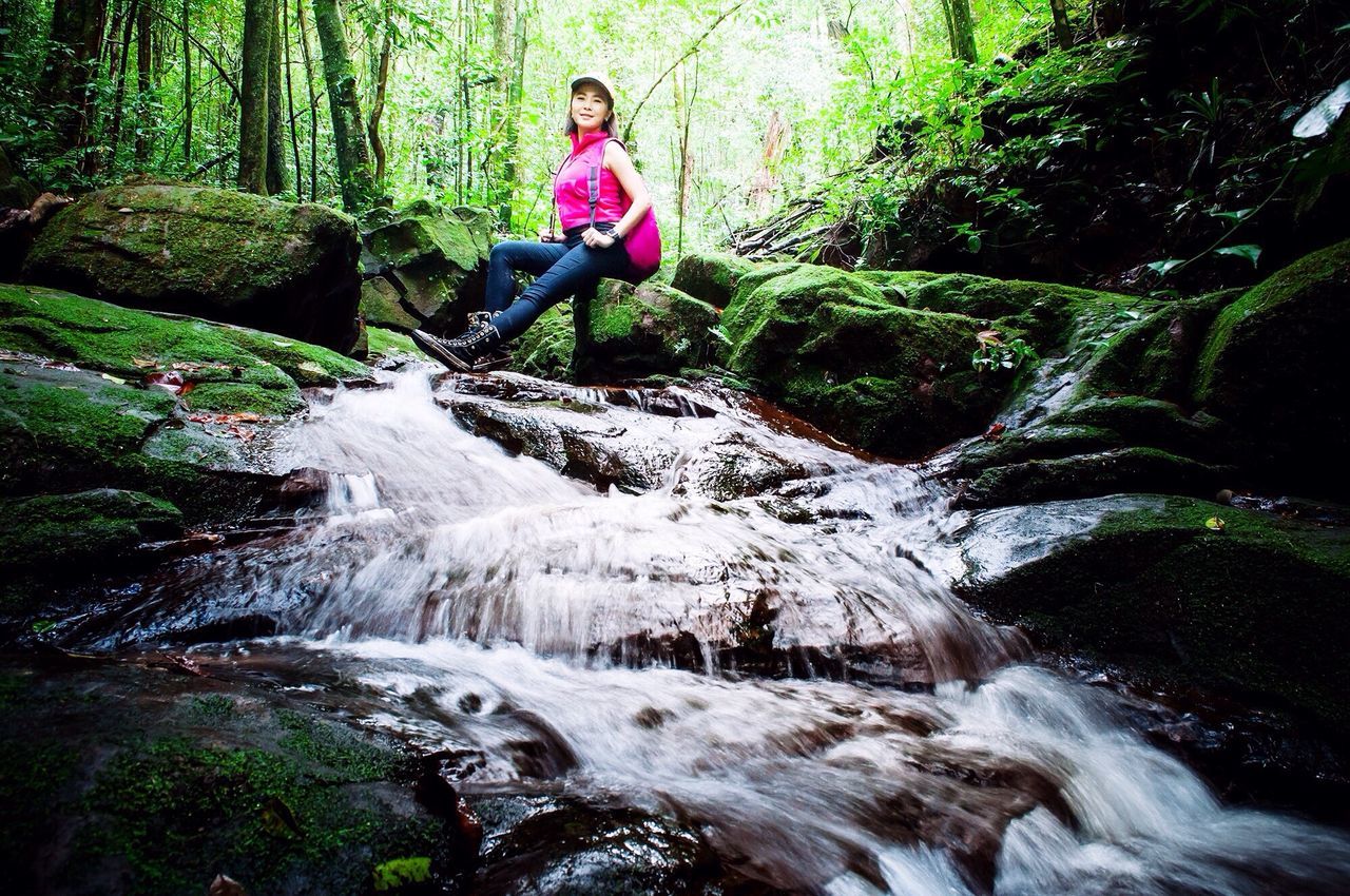 motion, waterfall, leisure activity, lifestyles, full length, tree, forest, water, flowing water, rock - object, long exposure, nature, beauty in nature, casual clothing, vacations, flowing, person, young adult