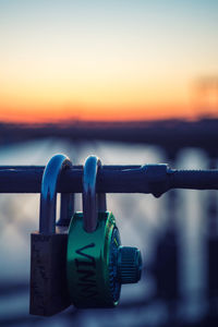 Close-up of metallic container against sea during sunset