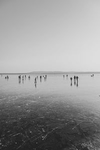 Silhouette people at beach against clear sky