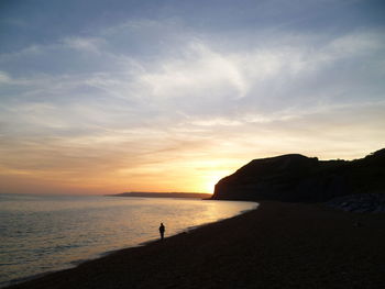 A person alone on a beach at sunset