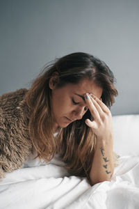 Portrait of woman lying down on bed at home