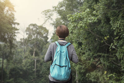Rear view of woman with blue backpack standing in forest