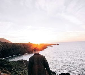 Rear view of a man overlooking calm sea