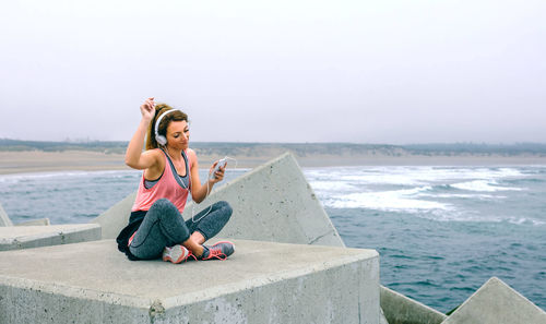 Woman sitting on pier against sky