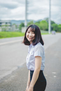 Portrait of smiling woman standing on road