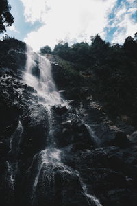 Scenic view of waterfall in forest against sky