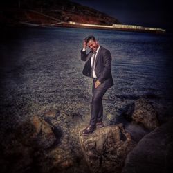 Full length of man standing on rock at beach