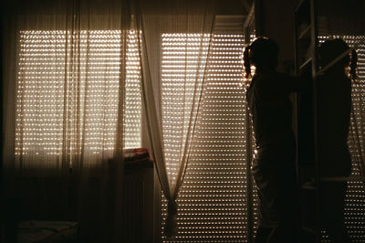 Silhouette of man standing on window