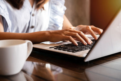 Midsection of businesswoman using laptop in office