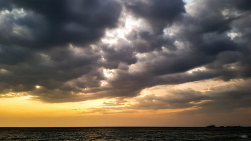 Scenic view of sea against dramatic sky during sunset