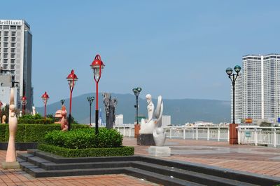 Statue by buildings against sky in city