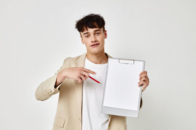 Portrait of smiling man showing clipboard against gray background