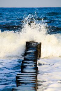 Sea waves splashing on shore against sky