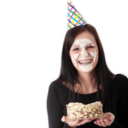 Portrait of smiling young woman holding ice cream against white background