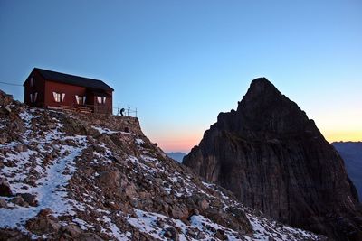 Low angle view of house on cliff against clear sky in winter