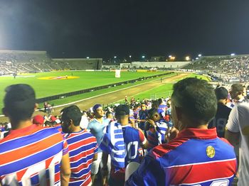 Rear view of people looking at soccer field at night