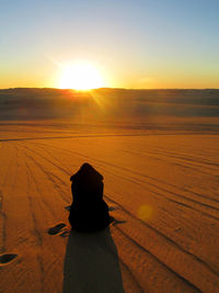 Silhouette person on landscape against sky during sunset