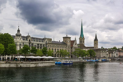 View of buildings at waterfront against cloudy sky