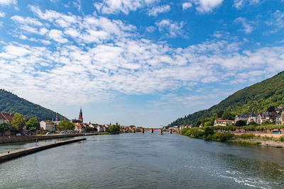 Arch bridge over river by buildings against sky