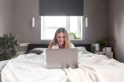 Portrait of a young woman sitting on bed at home