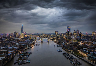 River amidst buildings in city against cloudy sky