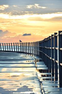 Pier over sea against sky during sunset