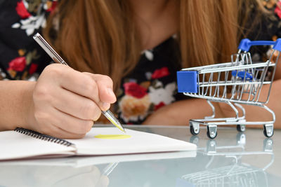 Midsection of woman holding paper while sitting on table