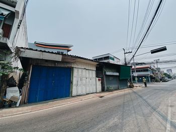 Empty road by buildings against clear sky