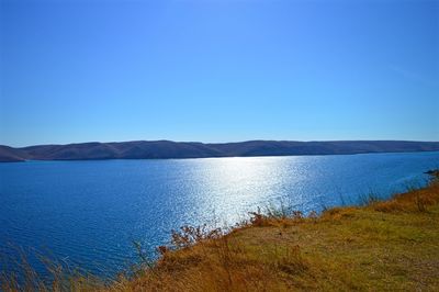 Scenic view of lake against clear blue sky
