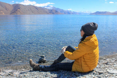 Side view of woman sitting by lake