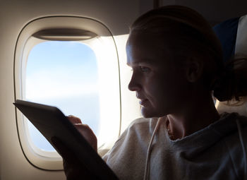Woman using digital tablet while sitting in airplane