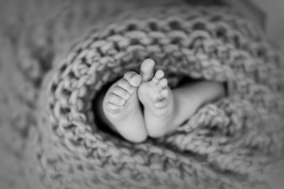 Newborn baby feet wrapped in knitted blanket in black and white