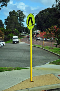 Road sign by street against sky