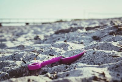 Pink shovel in sand on beach
