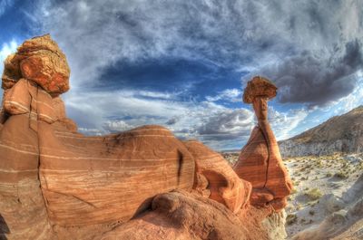 Rock formations in desert against cloudy sky