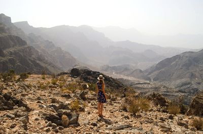 Woman standing on landscape against mountain range