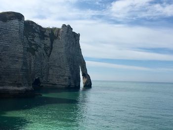 Rock formation by sea against sky