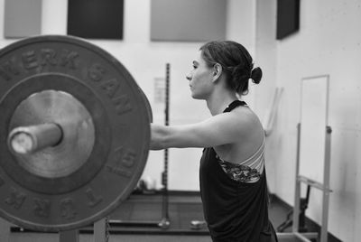 Young woman weight lifting in gym , side view 