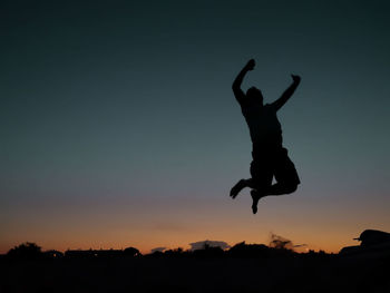 Silhouette man jumping against sky during sunset