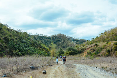 People riding bicycle on mountain against sky