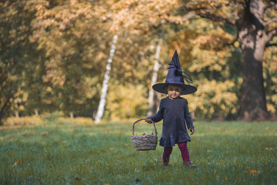 Full length of girl standing on grass against tree