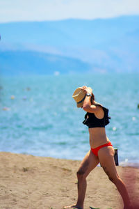 Full length of woman with arms raised on beach