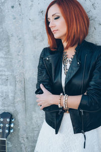 Young woman looking at camera while standing against wall