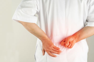 Rear view of doctor with backache against white background