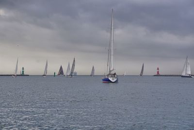 Sailboats sailing in sea against sky