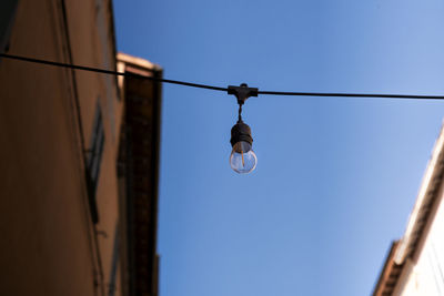 Low angle view of light bulb against blue sky