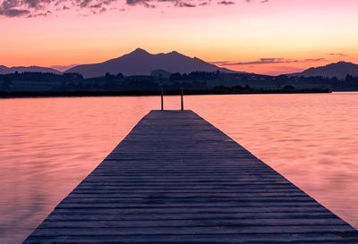 Pier over lake against sky during sunset