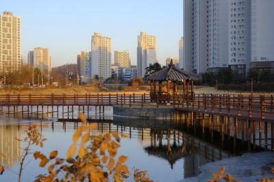 Reflection of buildings in city against clear sky